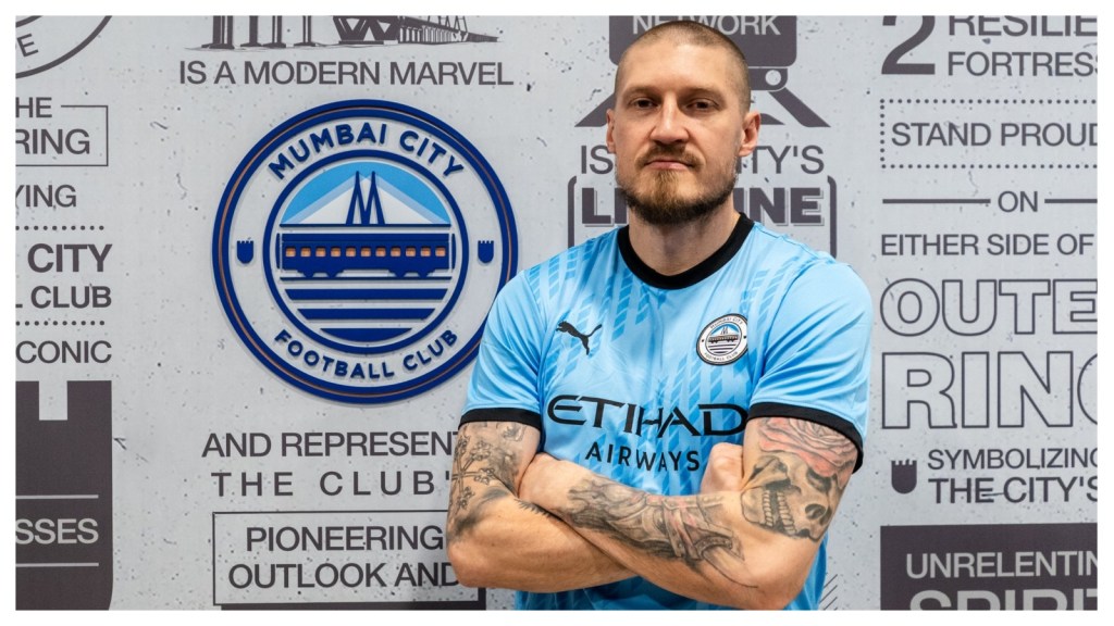 Joni Kauko poses next to the Mumbai City crest.